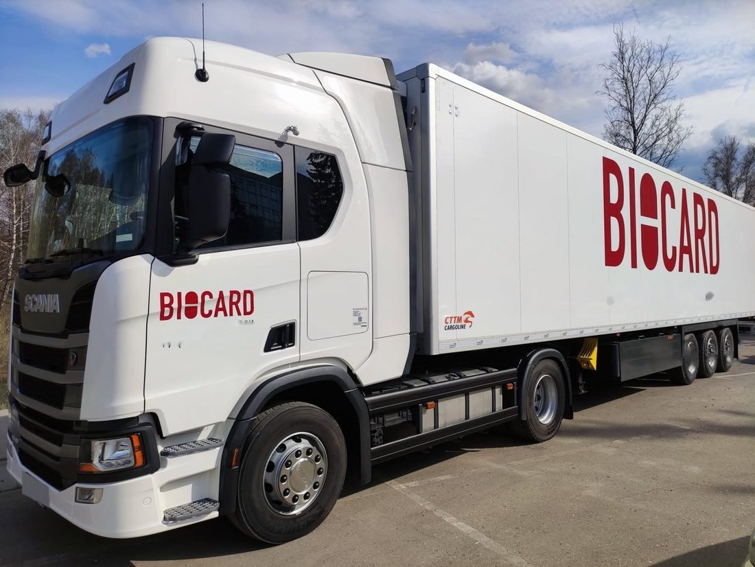 Белый тягач Scania с полуприцепом BIOCARD на площадке
