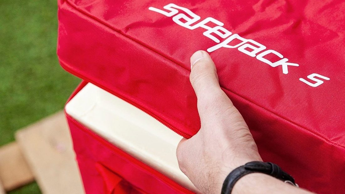 Красная сумка SafePack 5, рука держит её за край